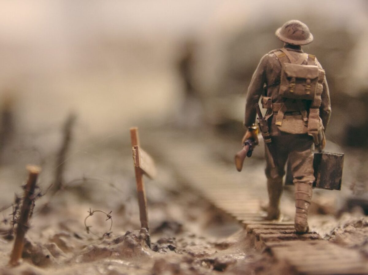 soldier walking on wooden pathway surrounded with barbwire selective focus photography