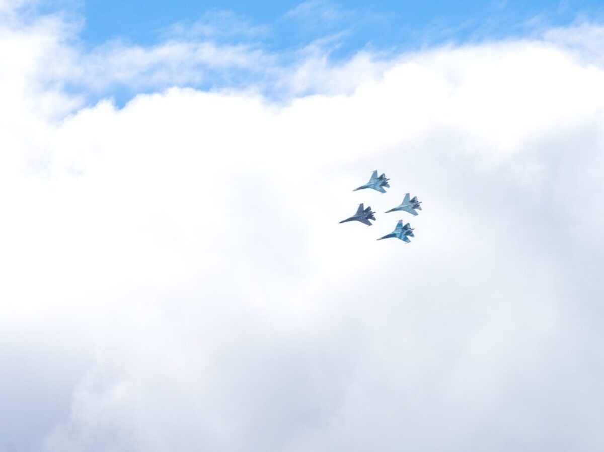 four blue fighting planes surrounded white clouds