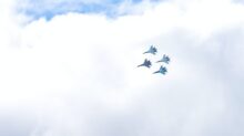 four blue fighting planes surrounded white clouds