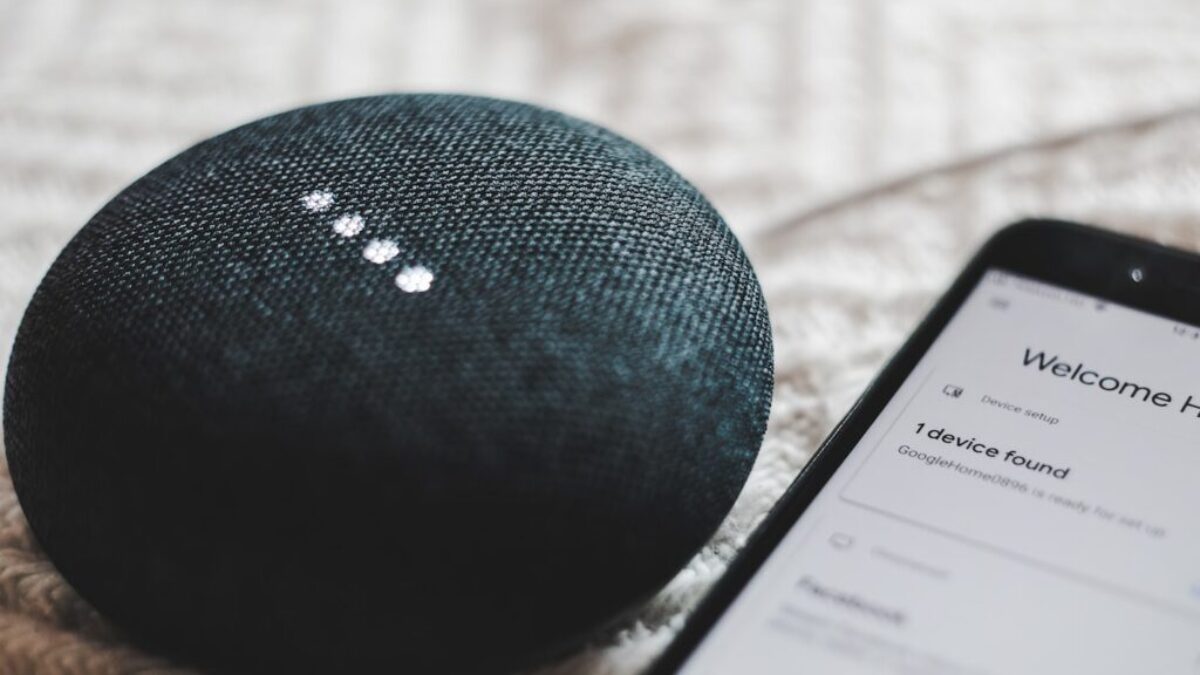 turned-on charcoal Google Home Mini and smartphone