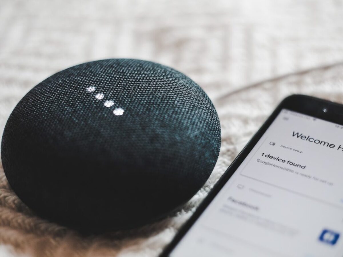 turned-on charcoal Google Home Mini and smartphone