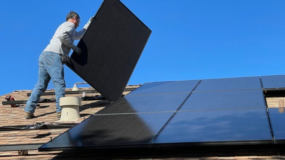 man in white dress shirt and blue denim jeans sitting on white and black solar panel