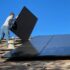 man in white dress shirt and blue denim jeans sitting on white and black solar panel