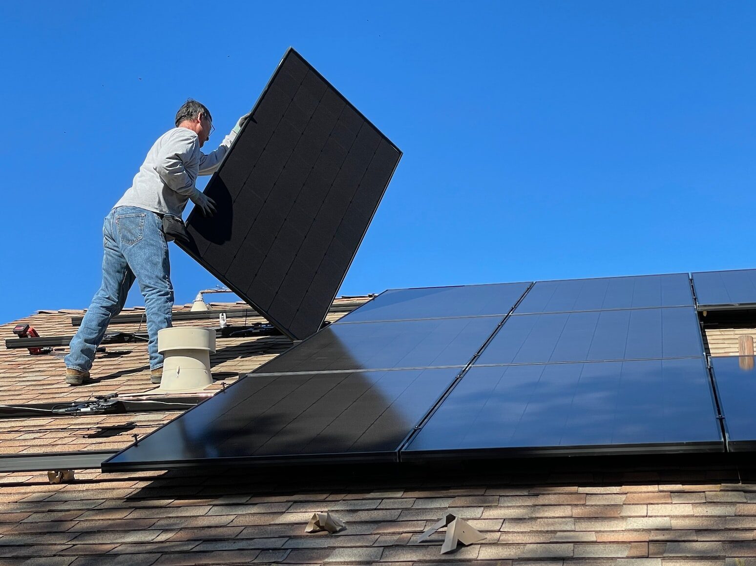 man in white dress shirt and blue denim jeans sitting on white and black solar panel