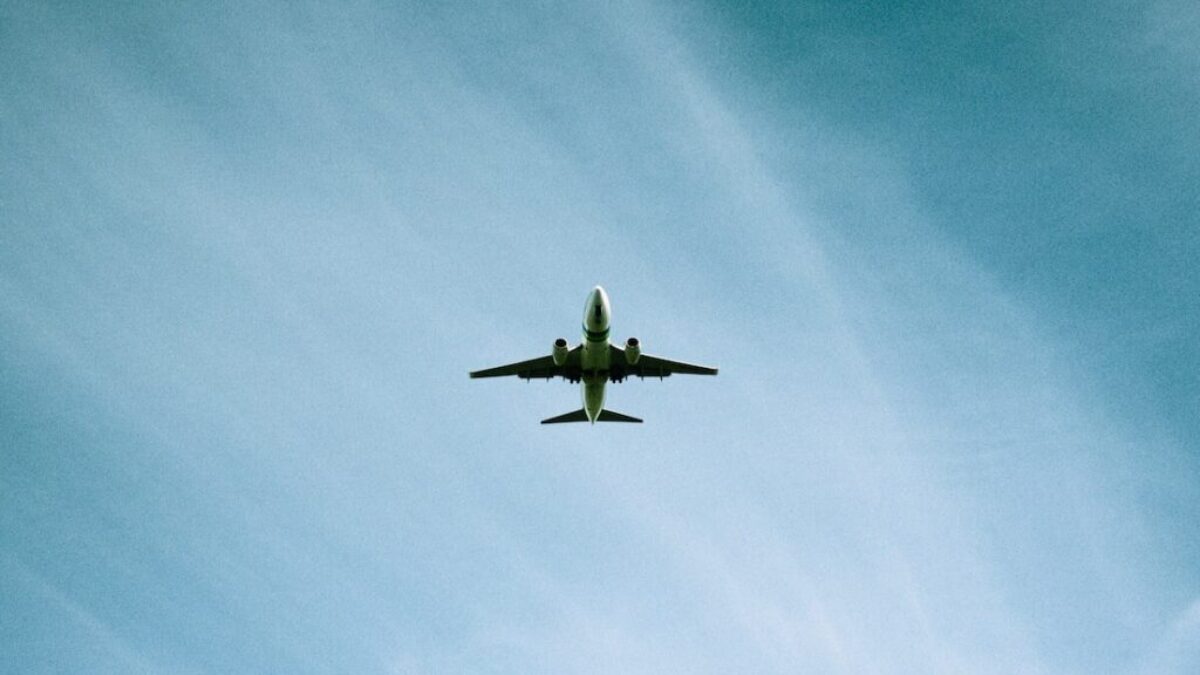 white airplane flying under blue sky