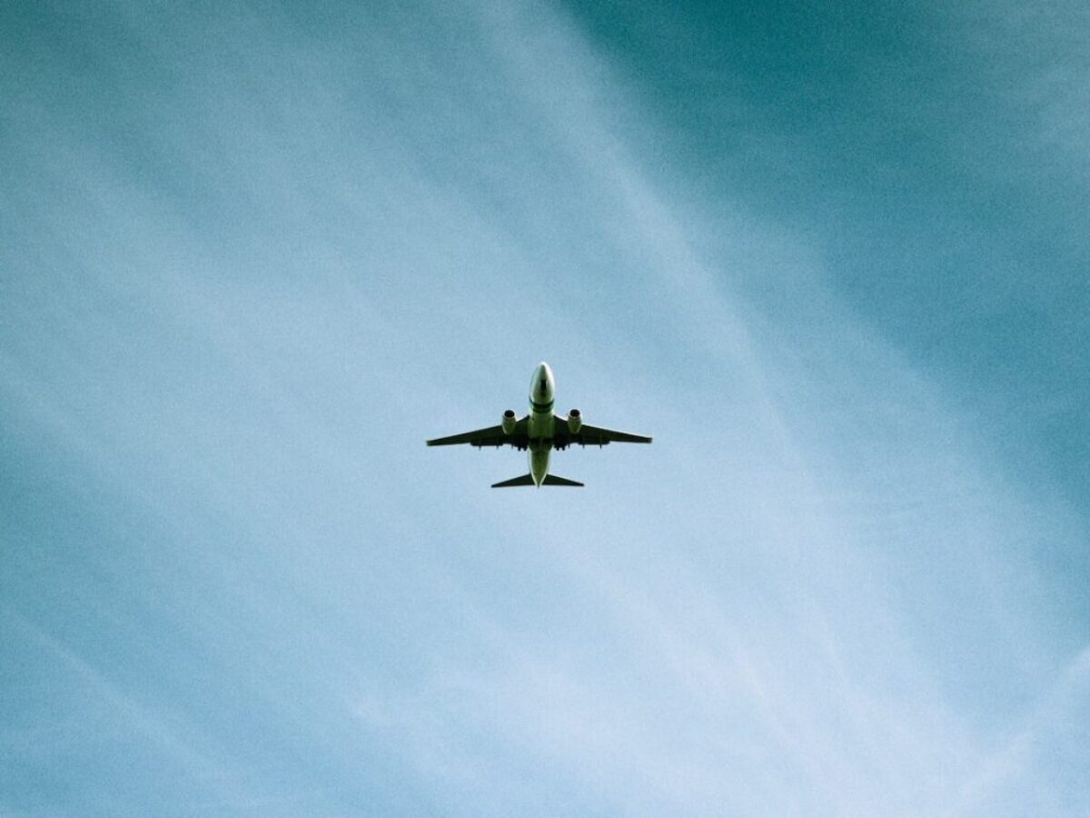 white airplane flying under blue sky