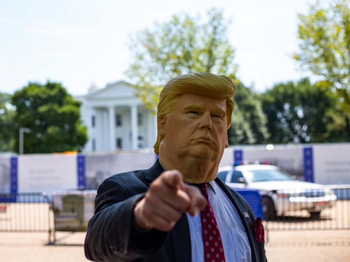 man wearing Donald Trump mask standing in front of White House