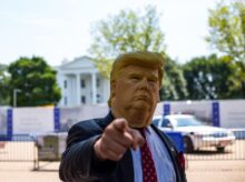 man wearing Donald Trump mask standing in front of White House