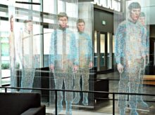 man in white and blue long sleeve shirt standing near glass window
