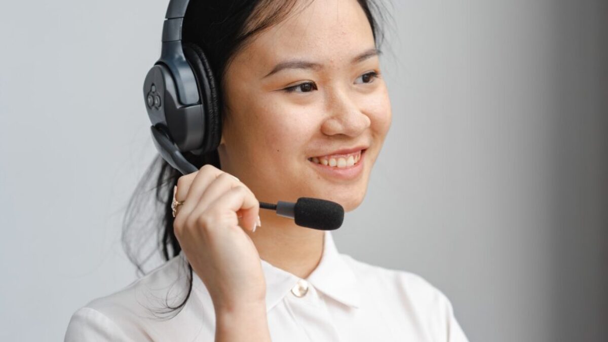 Close-Up Photo of a Woman Holding the Microphone of Her Black Headset