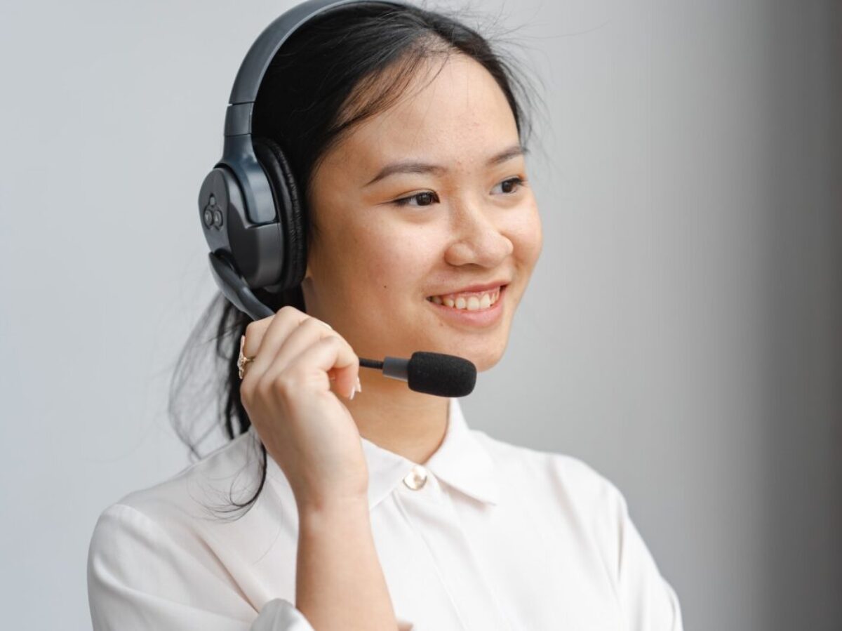 Close-Up Photo of a Woman Holding the Microphone of Her Black Headset