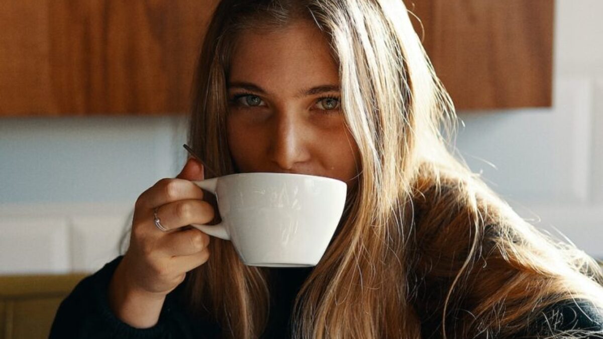 woman holding white ceramic teacup
