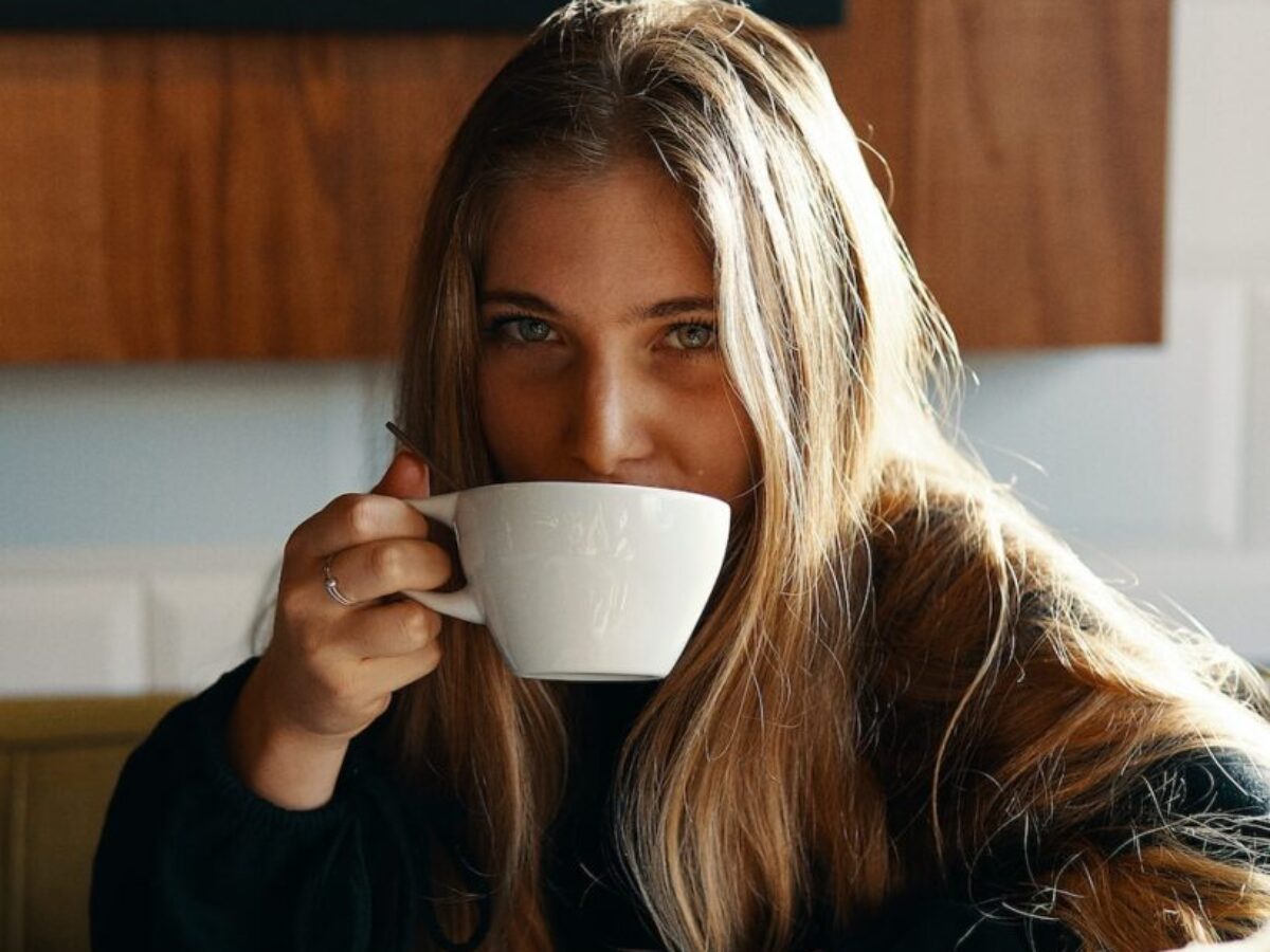 woman holding white ceramic teacup
