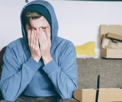 man covering face with both hands while sitting on bench