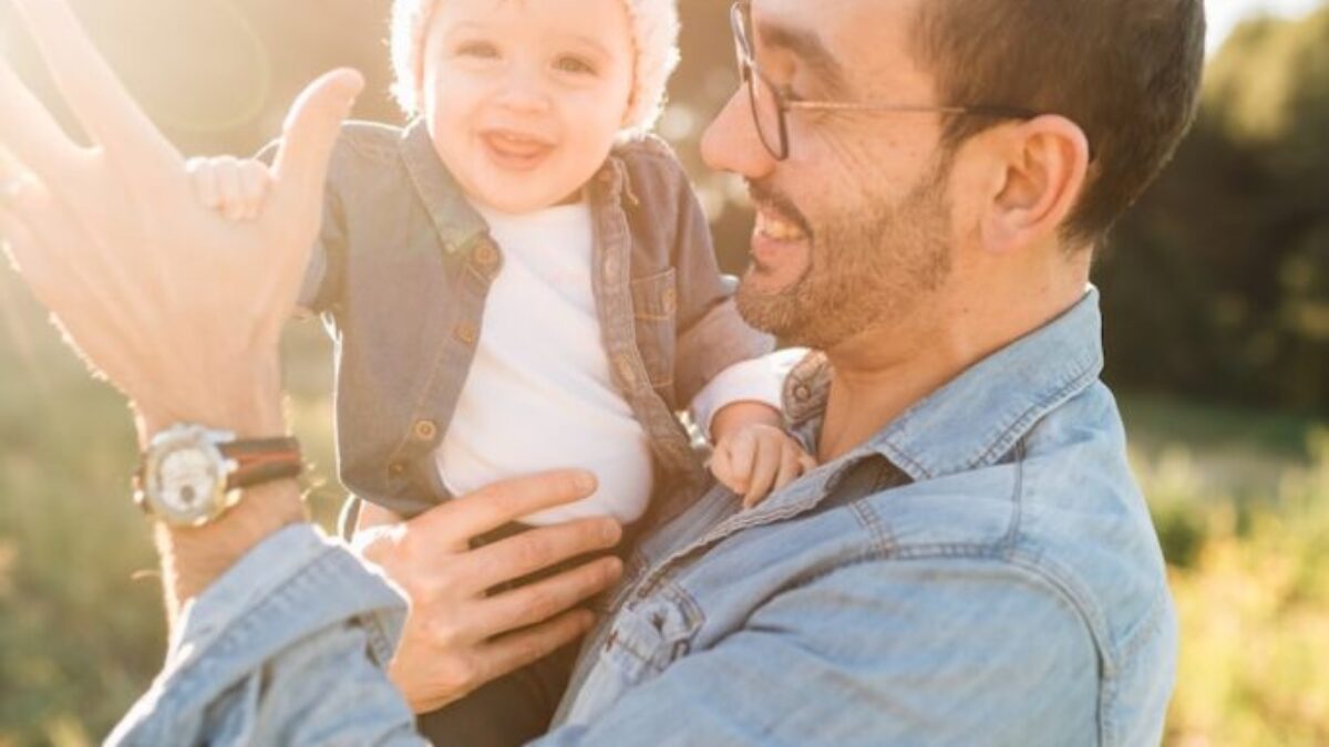 man in blue denim jacket carrying girl in white sweater during daytime