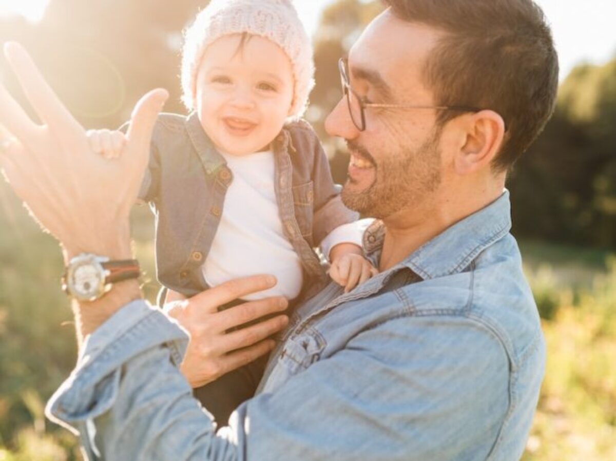 man in blue denim jacket carrying girl in white sweater during daytime