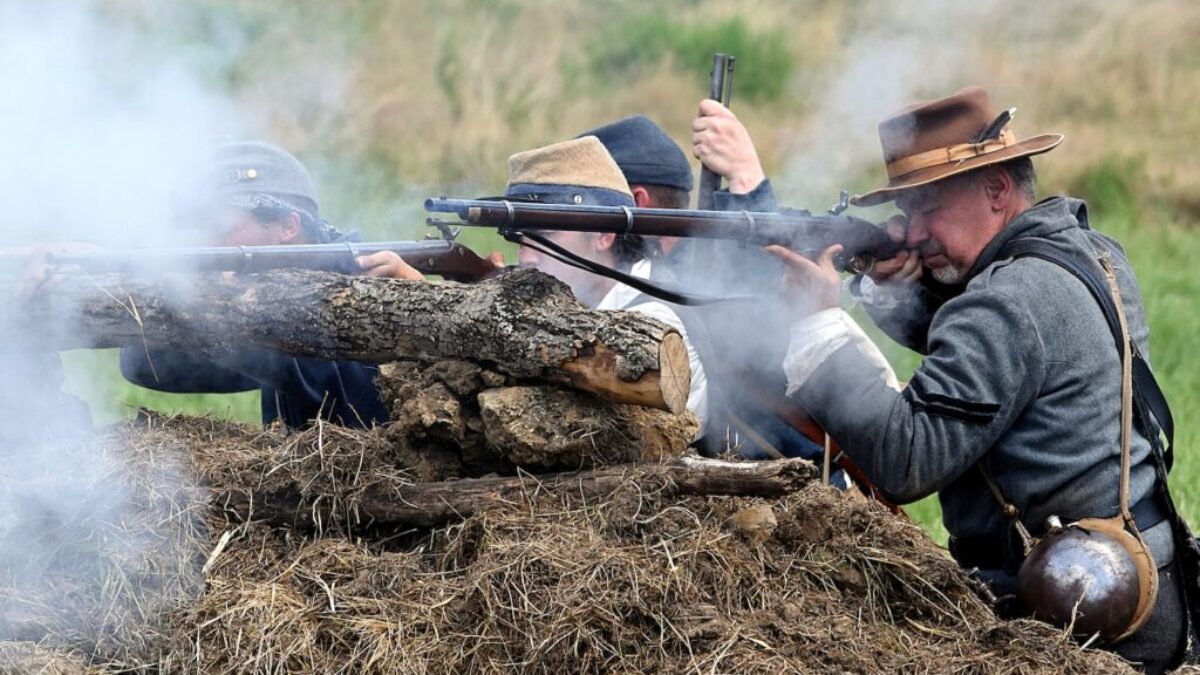 man in black jacket holding black rifle