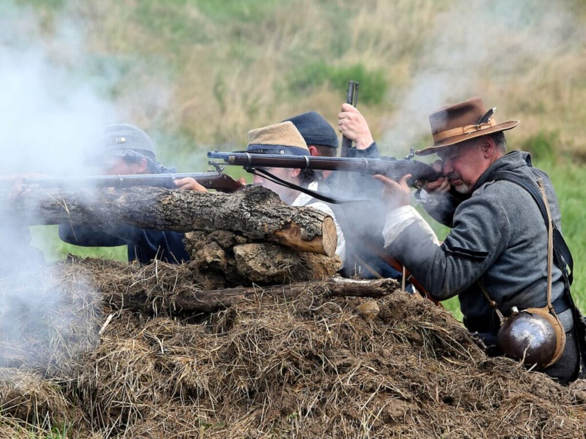 man in black jacket holding black rifle