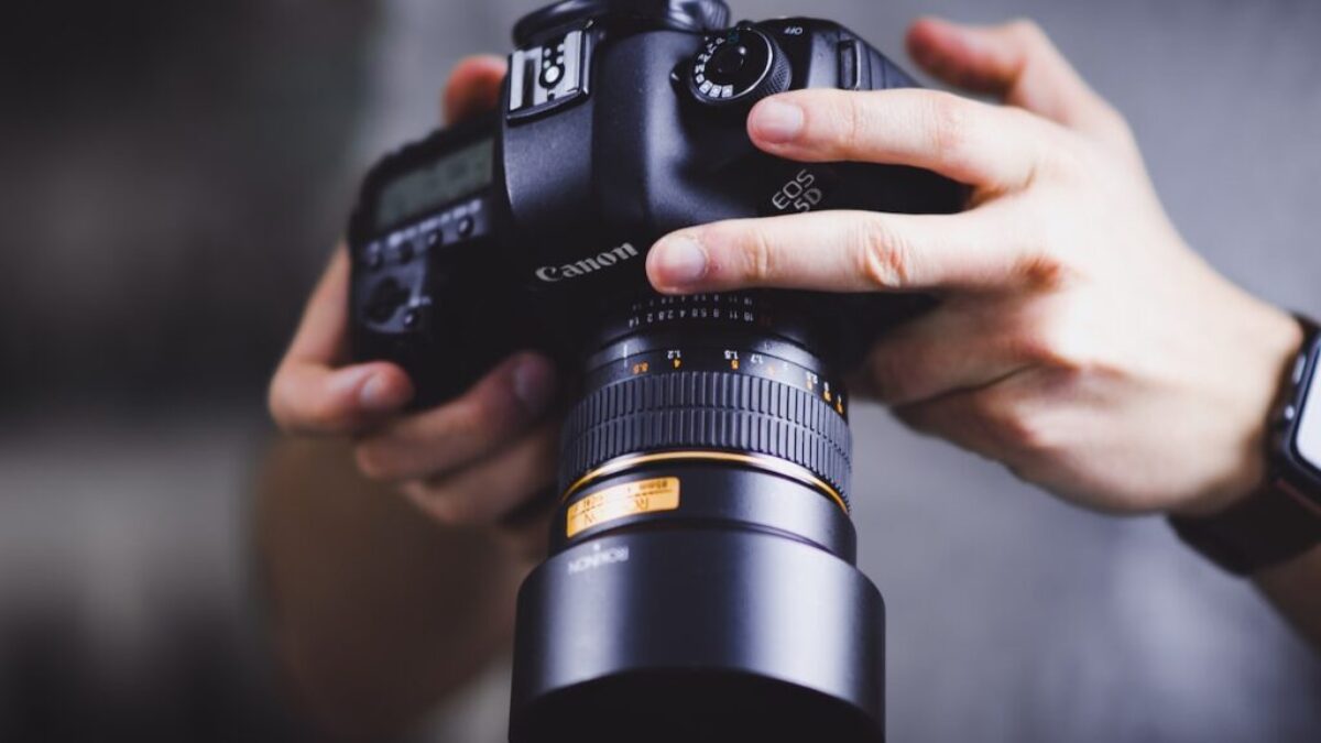 person holding Canon DSLR camera