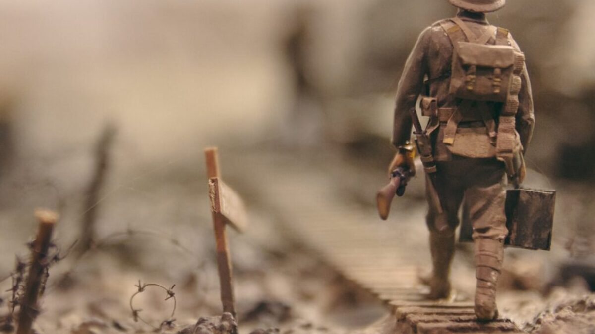 soldier walking on wooden pathway surrounded with barbwire selective focus photography