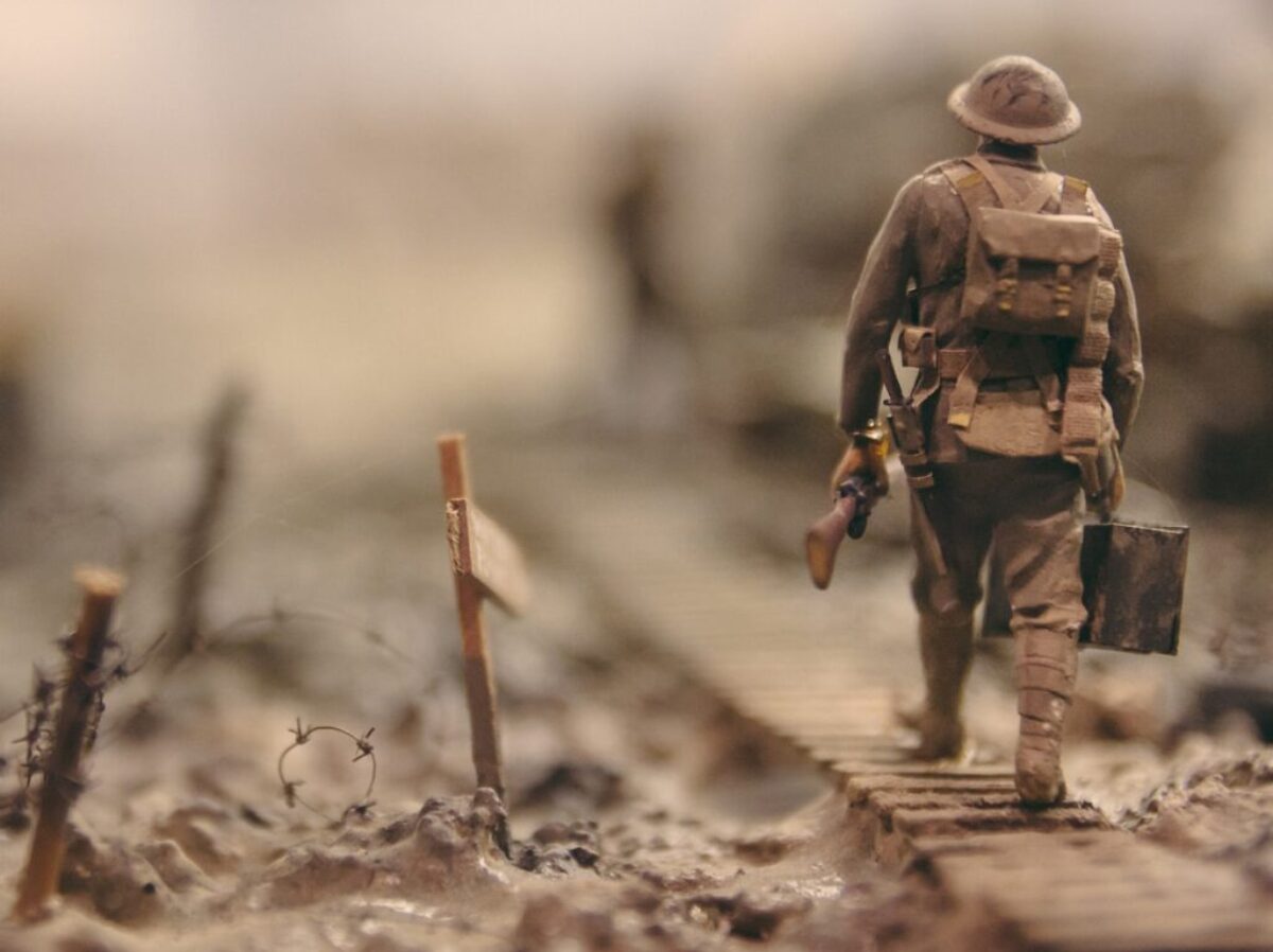 soldier walking on wooden pathway surrounded with barbwire selective focus photography