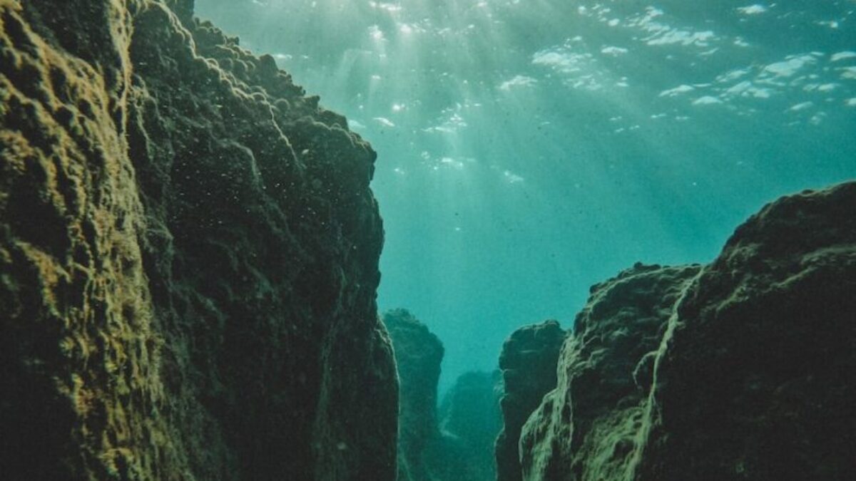 the sun shines through the water over rocks