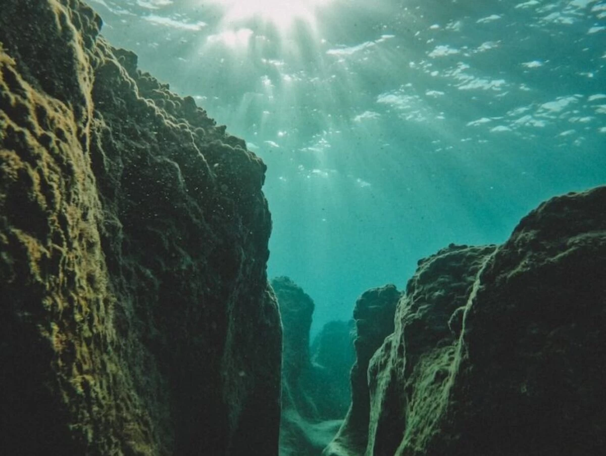 the sun shines through the water over rocks