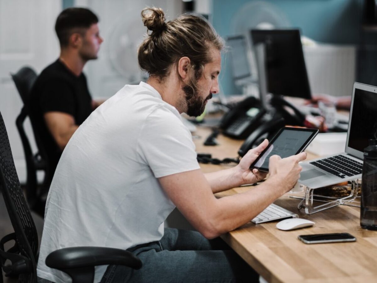 man holding turned-on iPad in front of turned-off MacBook Air