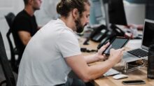 man holding turned-on iPad in front of turned-off MacBook Air