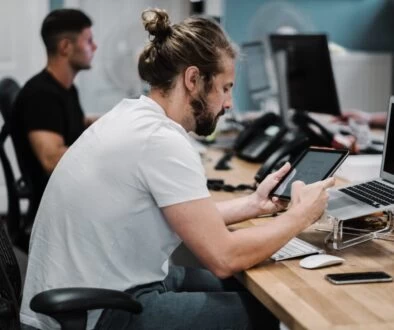 man holding turned-on iPad in front of turned-off MacBook Air