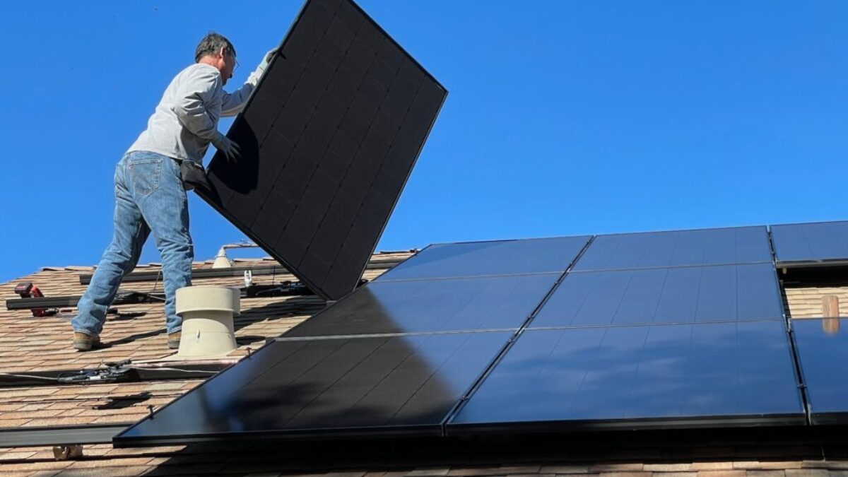 man in white dress shirt and blue denim jeans sitting on white and black solar panel