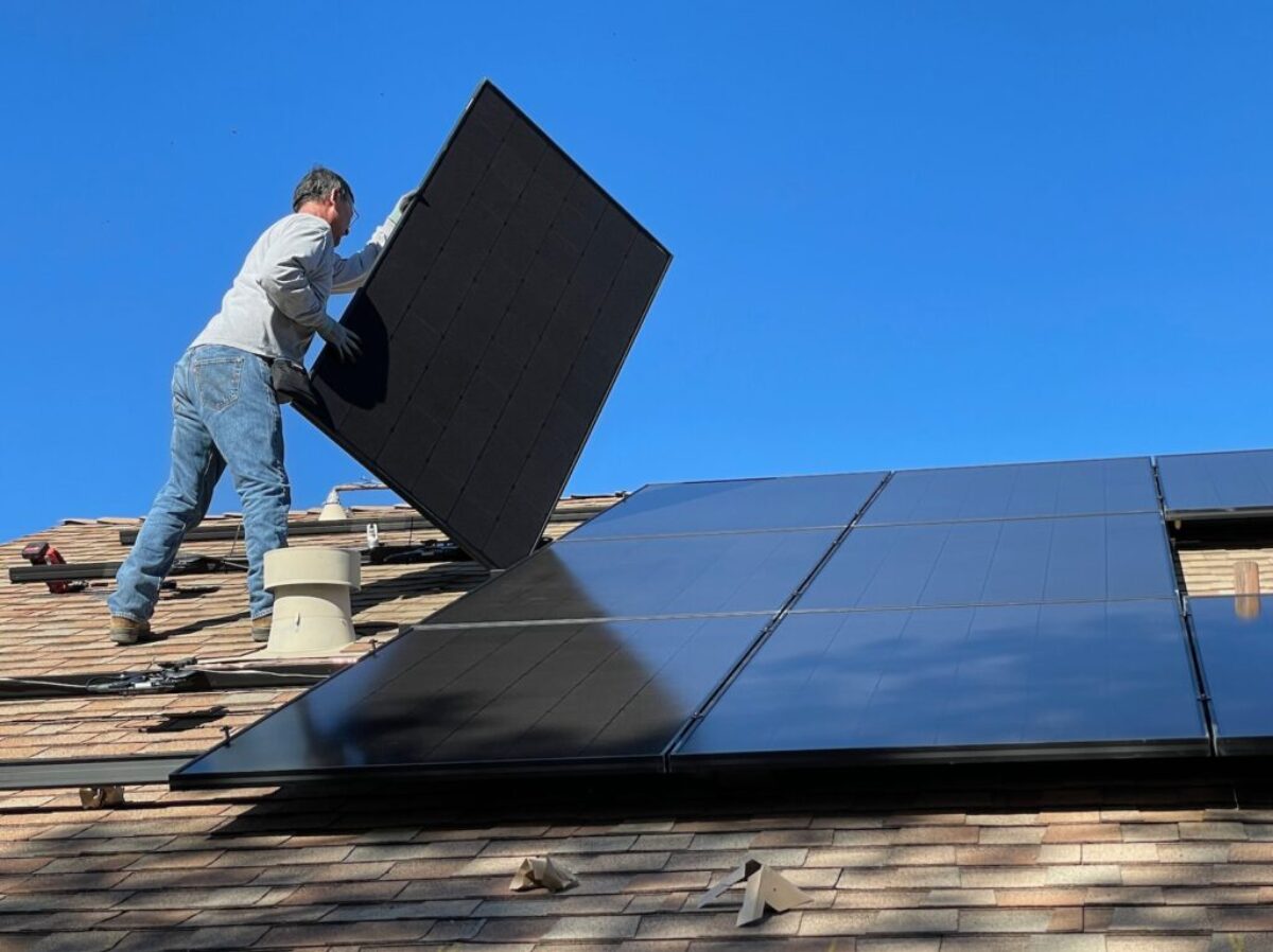 man in white dress shirt and blue denim jeans sitting on white and black solar panel