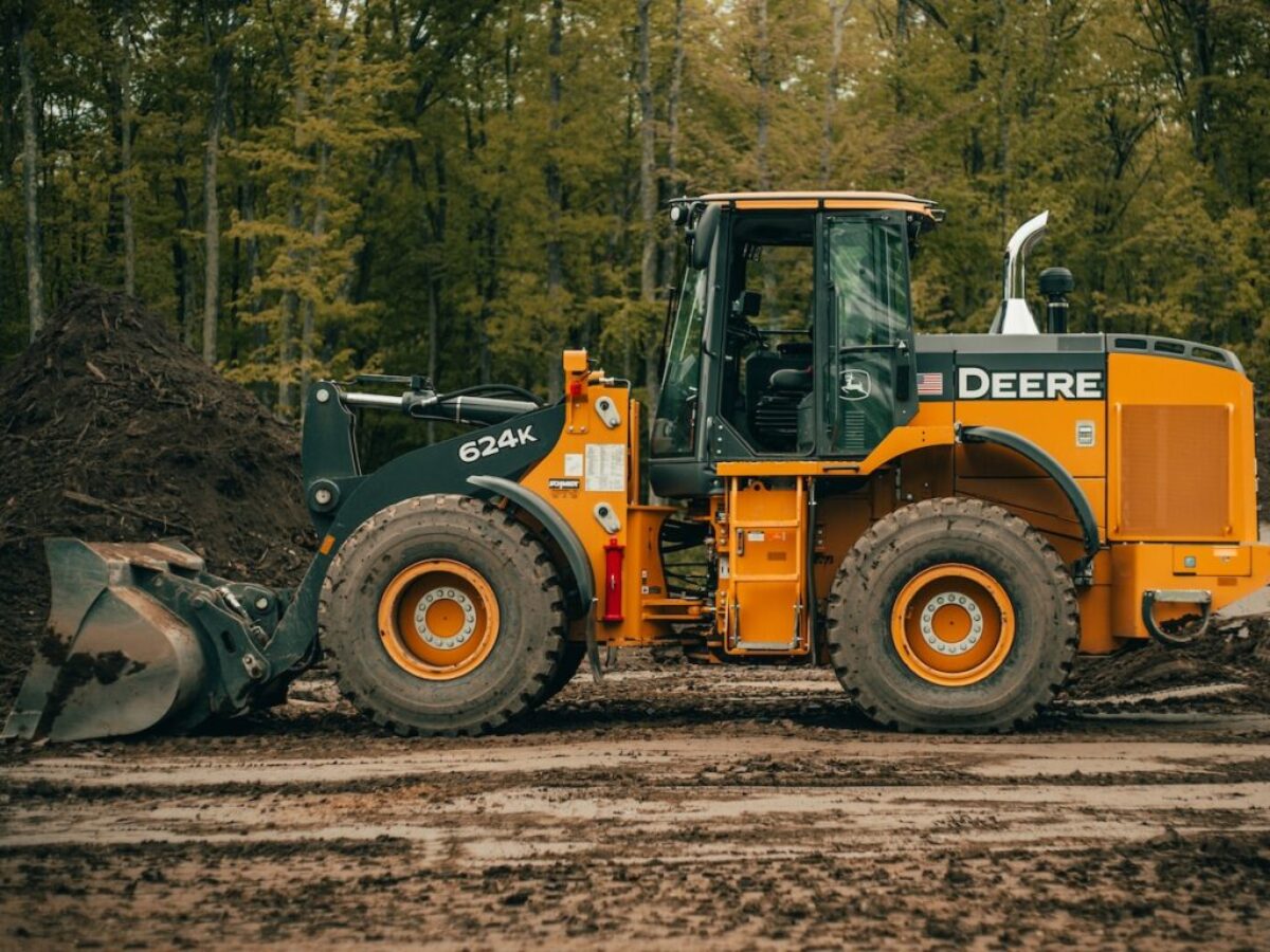 a tractor is parked in the dirt near a pile of dirt