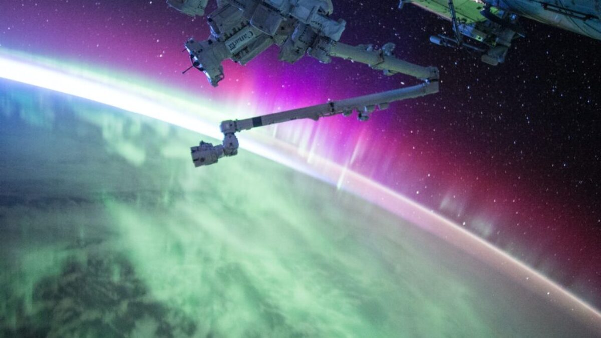 photography of purple and green aurora beam below grey space satellite
