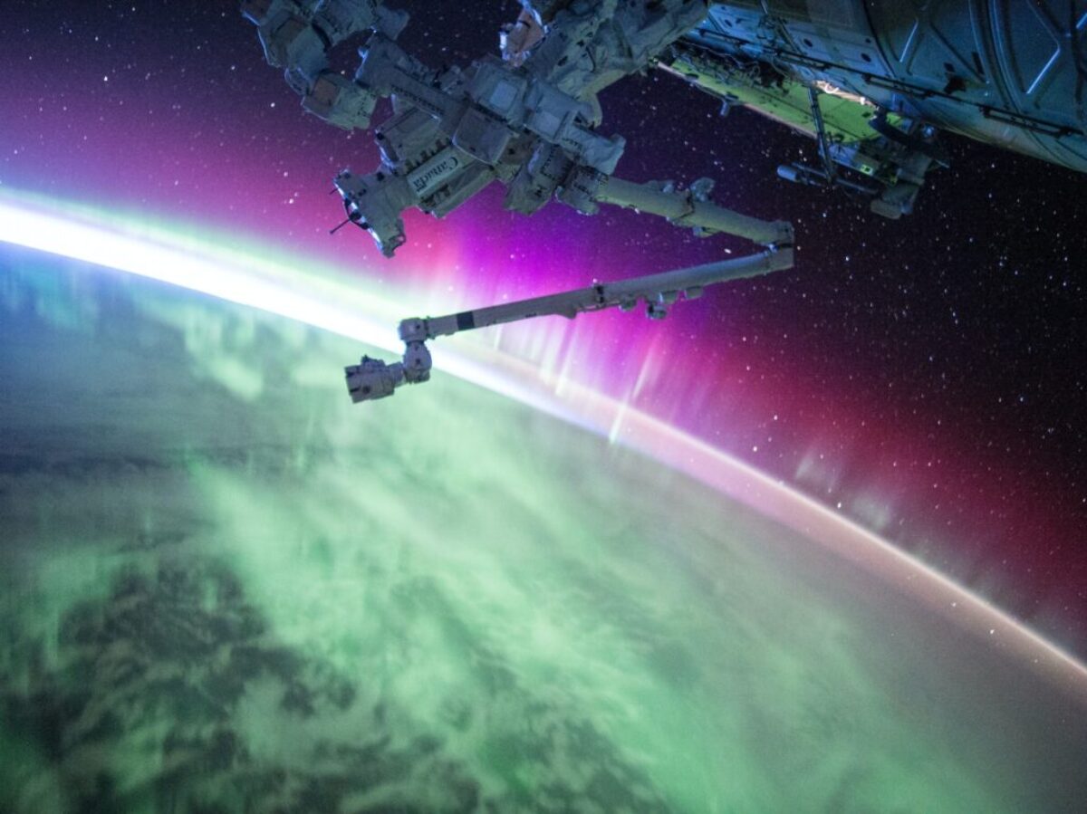 photography of purple and green aurora beam below grey space satellite