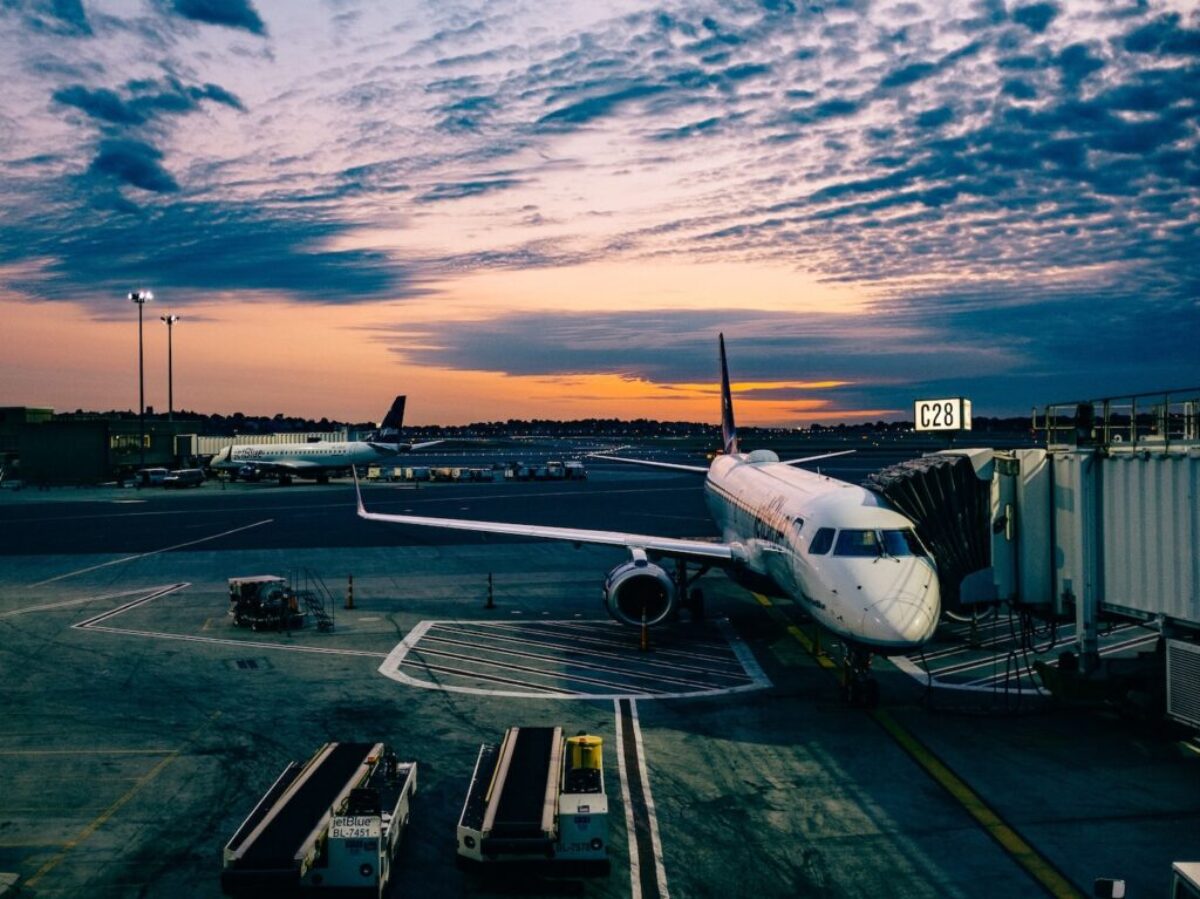 white airplane near trailers during sunset