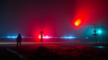 Unrecognizable Person Observing Red and Blue Lights on Road at Night