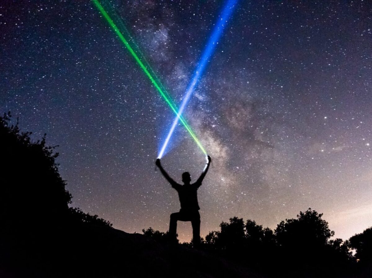 man holding green and blue flashlights