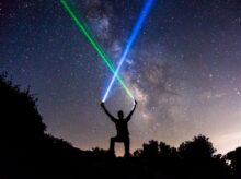 man holding green and blue flashlights