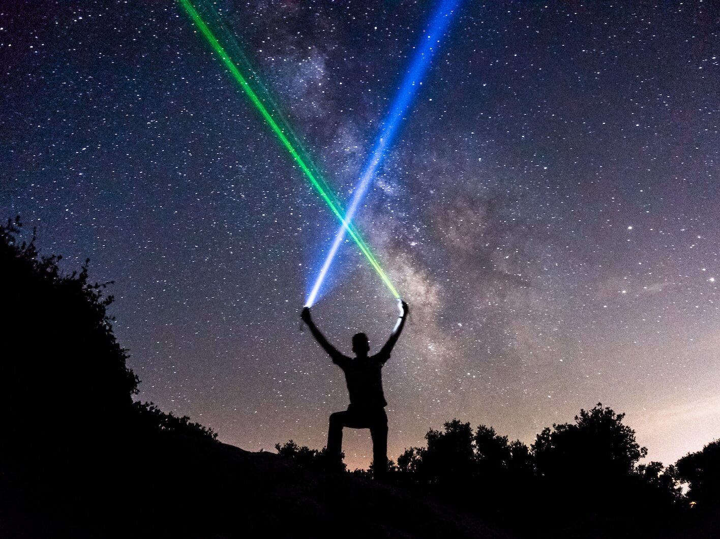 man holding green and blue flashlights