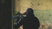 man in black jacket holding rifle