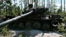 an old tank sitting in the middle of a forest