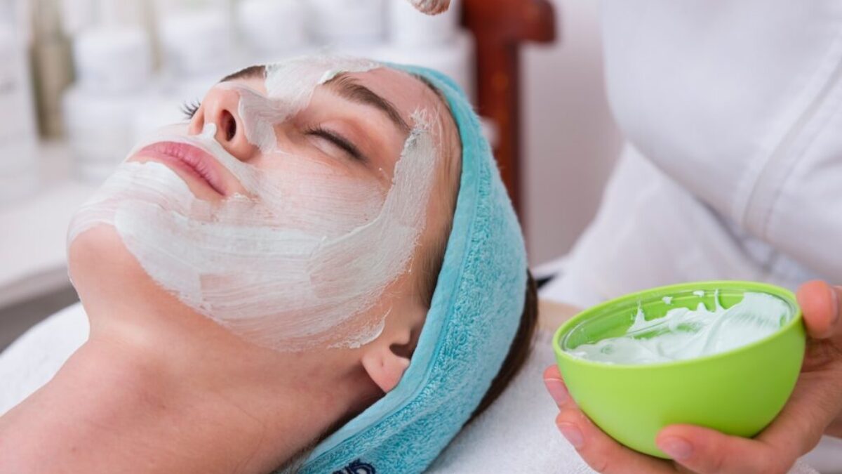 woman lying on blue towel with white cream on face