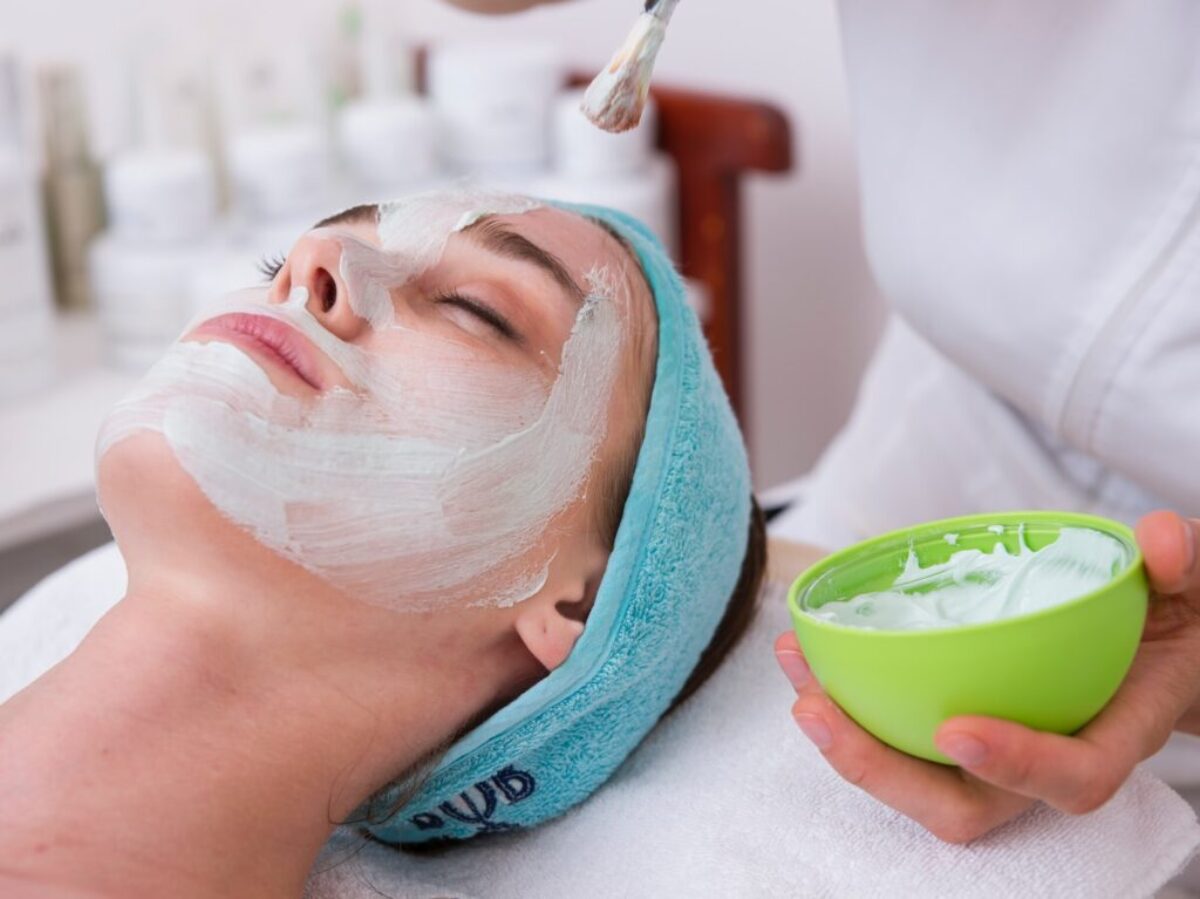 woman lying on blue towel with white cream on face
