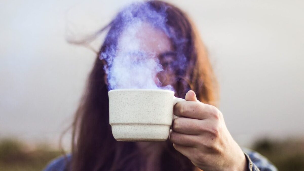 selective focus photo of man holding white ceramic coffee cup