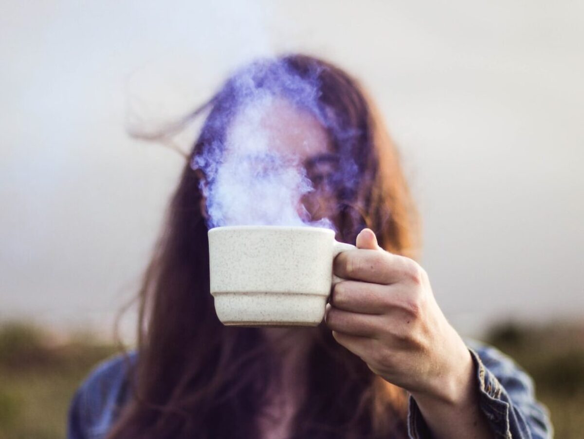 selective focus photo of man holding white ceramic coffee cup