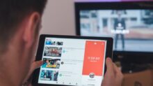 man browsing tablet sitting in front of TV