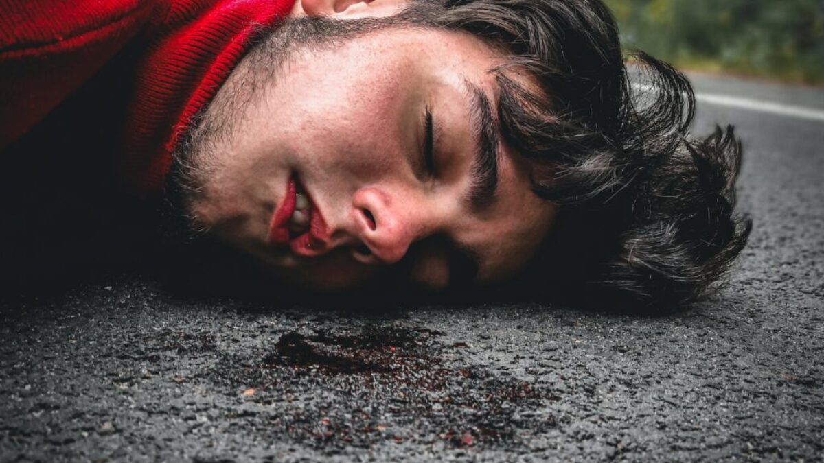 man in red sweater lying on ground during daytime
