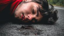 man in red sweater lying on ground during daytime