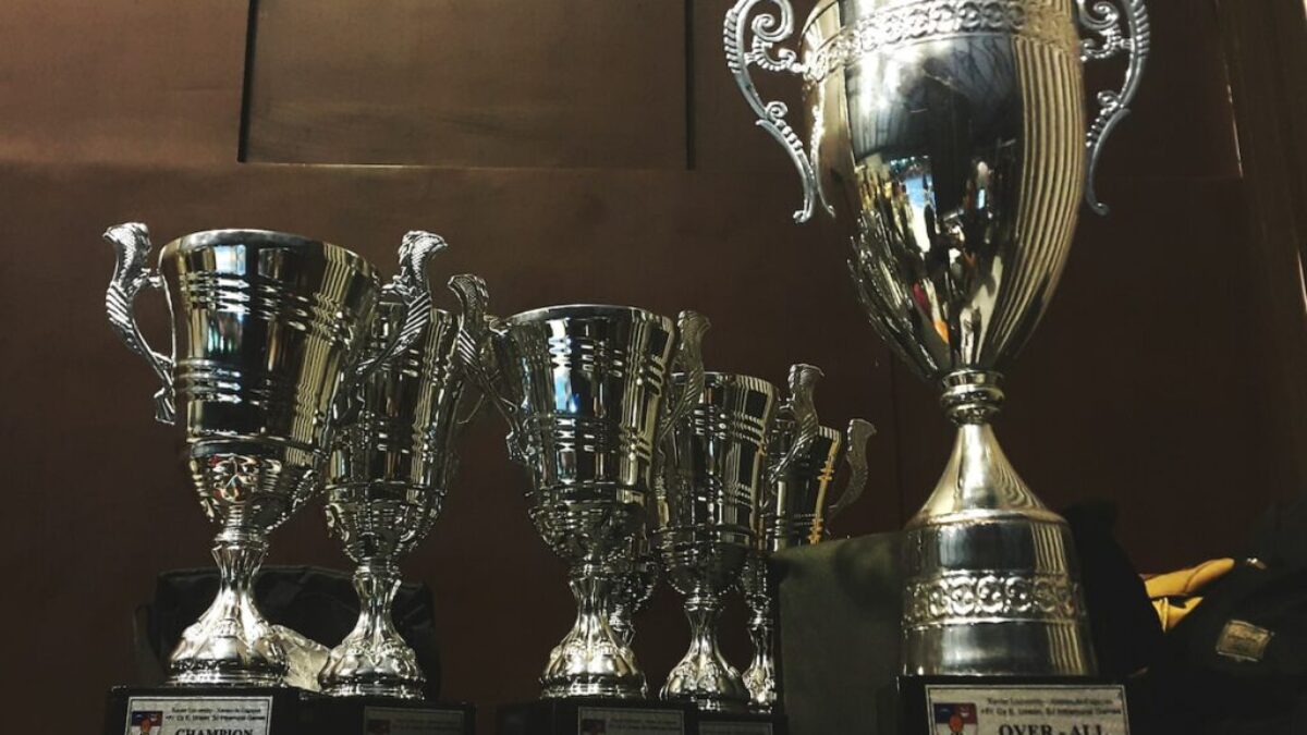 several silver and gold trophies on wooden surface